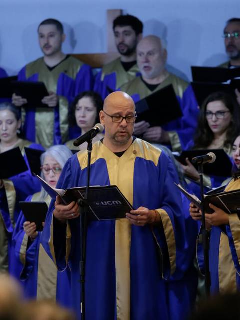 Un coro vestido con túnicas azules y doradas está cantando en un evento.