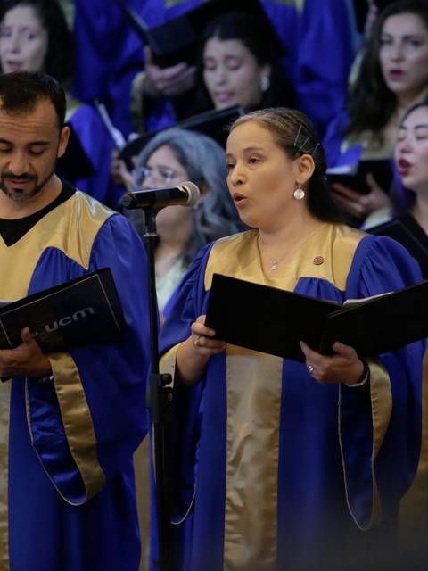 Un grupo de cantores con vestimenta azul y dorada interpretando una pieza musical en un evento.