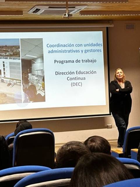 Una charla académica sobre educación continua en una sala llena de estudiantes.