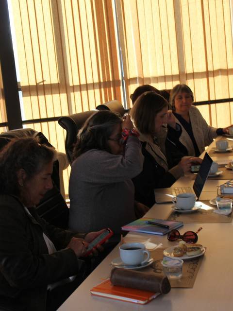 Una reunión de mujeres en una sala, conversando y trabajando en equipo.