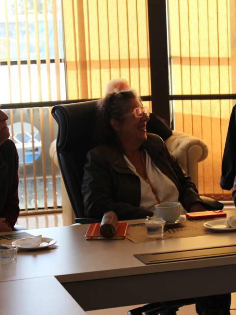 Un grupo de personas conversando en una reunión con vasos y tazas de café sobre una mesa.