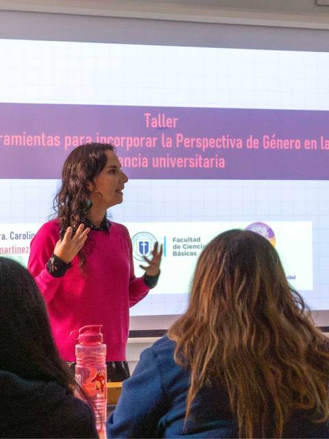 Una profesora presenta un taller sobre perspectiva de género en un aula universitaria.