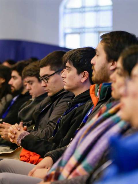 Un grupo de personas concentradas en una charla o conferencia en un auditorio.