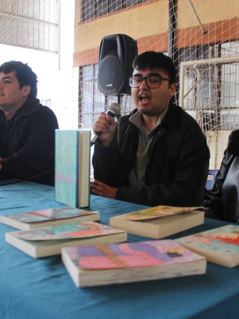 Una conversación en un evento literario con tres personas hablando y libros en una mesa.