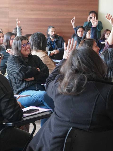 Un grupo de personas levantando la mano en una reunión.