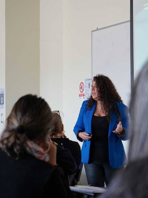 Una profesora está dando una charla a un grupo de estudiantes en un salón de clases.