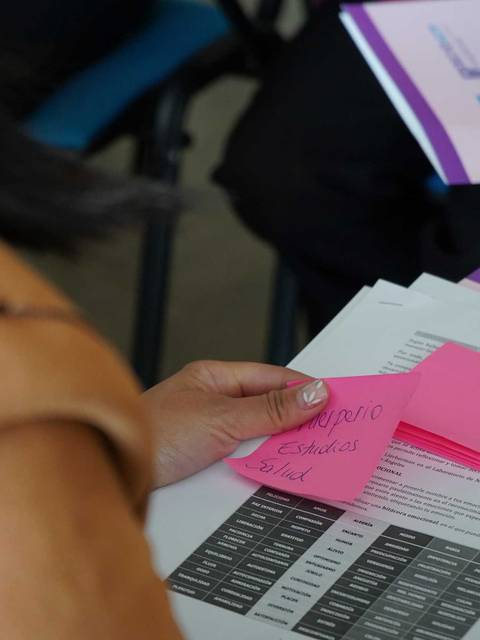 Una persona está revisando documentos con notas adhesivas en una reunión.