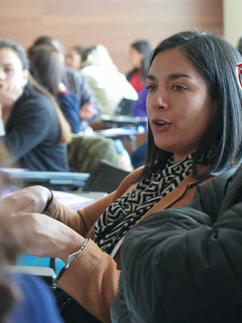 Dos mujeres conversando animadamente en un ambiente de aula.