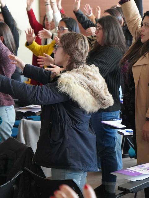 Un grupo de mujeres participando activamente en una actividad en conjunto, levantando las manos con entusiasmo.