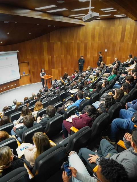 Una charla llena de gente en un auditorio moderno y acogedor.