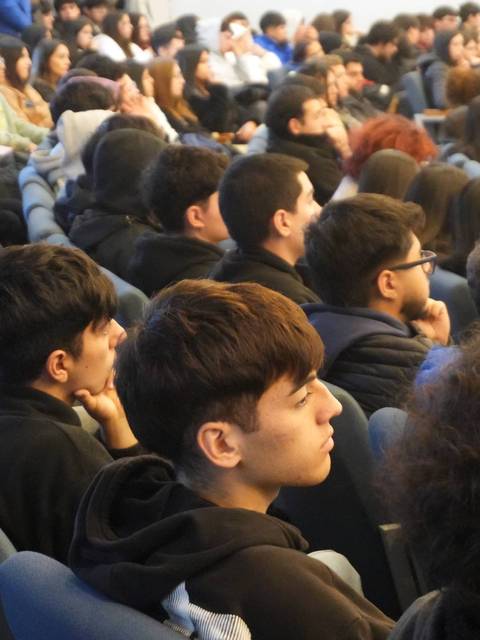 Un grupo de jóvenes atentos en una charla en un auditorio.