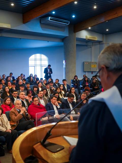 Un evento comunitario con una gran cantidad de personas prestando atención a un orador en un anfiteatro.