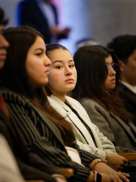 Un grupo de jóvenes escuchando atentamente durante un evento formal.