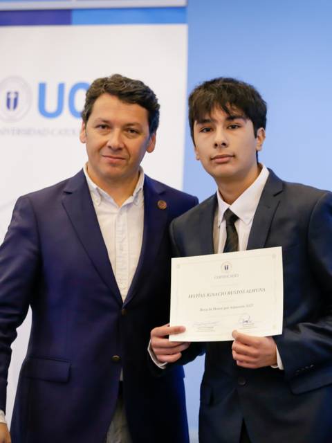 Dos personas posando con un certificado en una ceremonia de graduación en la UGC.