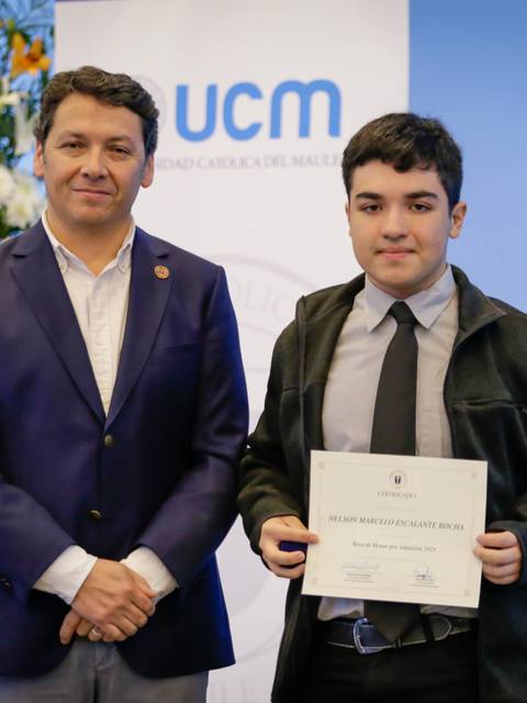 Este es un momento de orgullo donde un joven recibe su certificado acompañado de un adulto en un evento destacado.