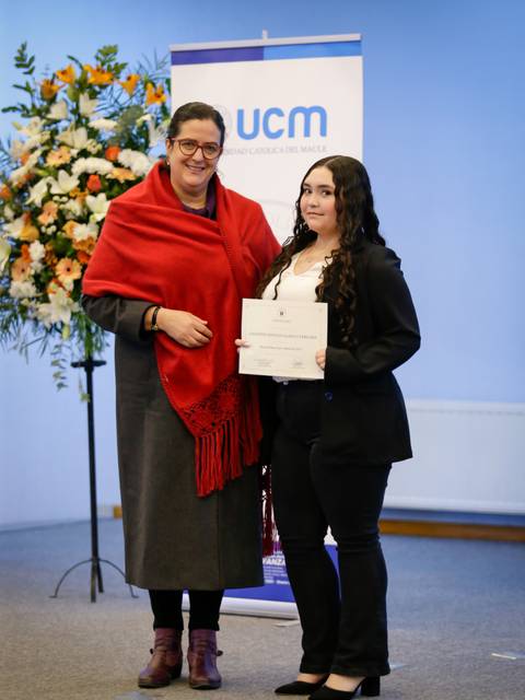 Dos mujeres posando durante una ceremonia de entrega de certificados en un evento formal.