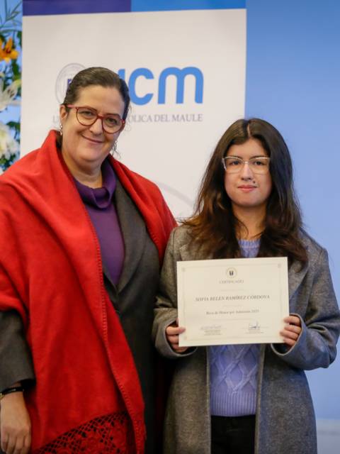 Una joven recibe un certificado con una sonrisa en un acto solemne.