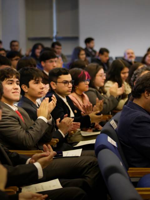 Una multitud aplaudiendo durante un evento en un auditorio.
