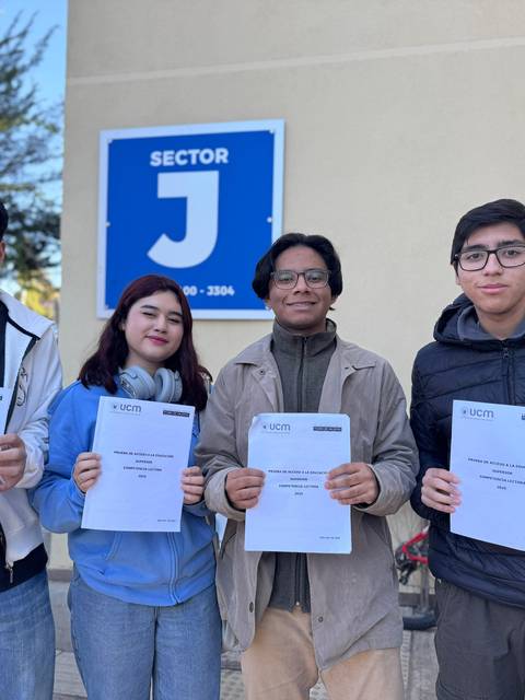 Cuatro estudiantes posan con sus certificados frente a un cartel que dice 'Sector J'.