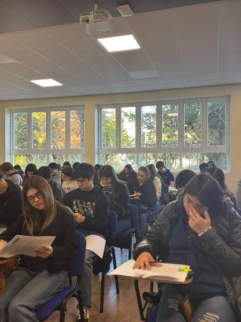 Un grupo de estudiantes en un salón de clases concentrados en un examen.
