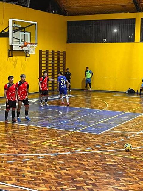 Partido de futsal en una cancha con un ambiente de competencia y camaradería.
