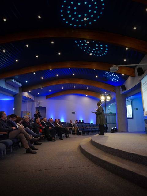 Una charla inspiradora en un auditorio iluminado de azul.