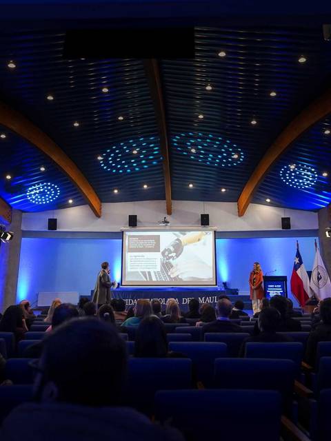 Un auditorio lleno de gente escuchando a un presentador en una conferencia.
