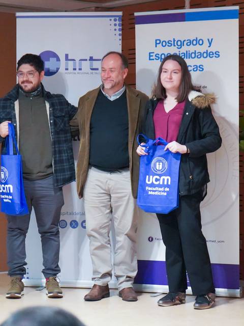 Tres personas posando con bolsas de la universidad en un evento formal.