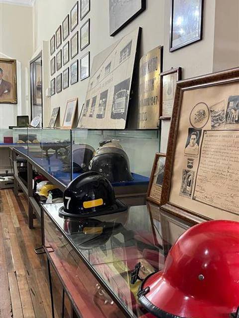 Una vitrina con cascos de bomberos y documentos históricos en un museo chileno.