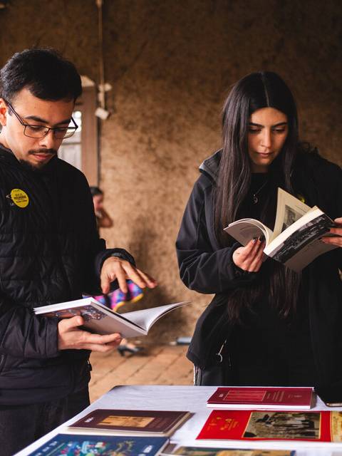 Dos personas revisando libros en un ambiente rústico y acogedor.