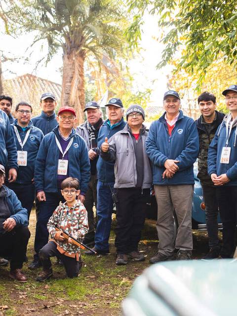 Grupo de entusiastas de autos clásicos posando alegremente en un evento en Chile.