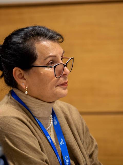 Una mujer con gafas que escucha atentamente en una reunión.