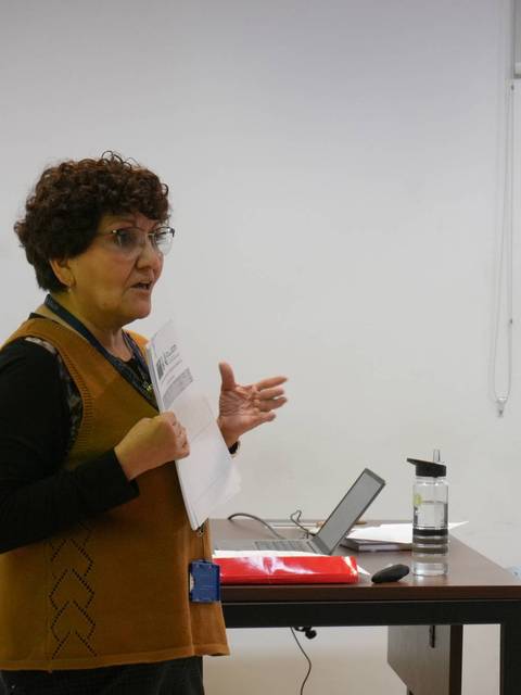Mujer exponiendo en un taller sobre el cáncer en una sala de reuniones.