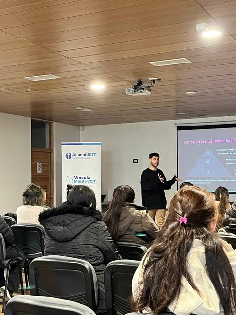 Un hombre está haciendo una presentación en una sala de clases frente a un grupo de personas.