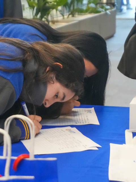 Dos personas llenando formularios en una mesa.