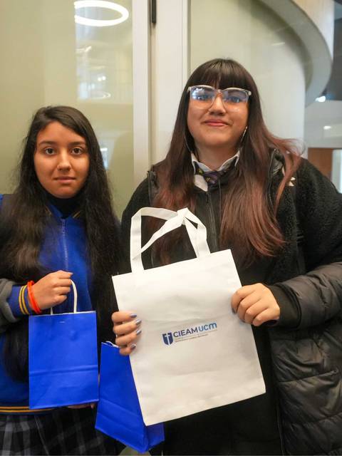 Dos jóvenes posando con bolsas en un lugar moderno.