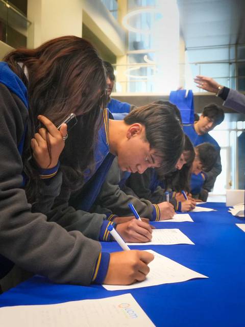 Un grupo de estudiantes está llenando formularios en una actividad organizada.