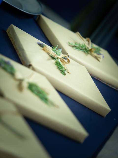 Una mesa con regalos envueltos en papel marrón decorados con hierbas.