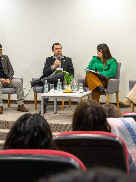 Un panel de discusión en una institución educativa con cuatro expositores compartiendo sus ideas.