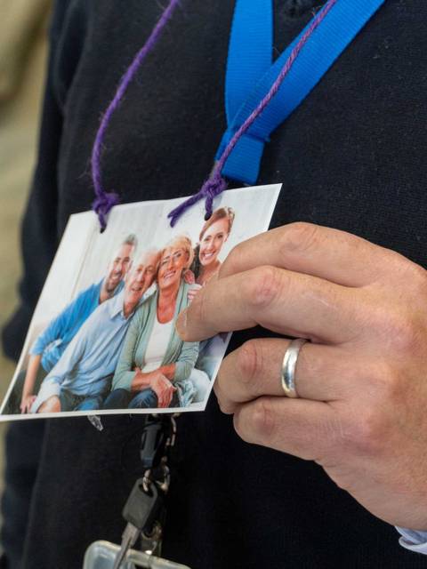 Una persona sostiene una foto de un grupo de amigos sonriendo en un evento.