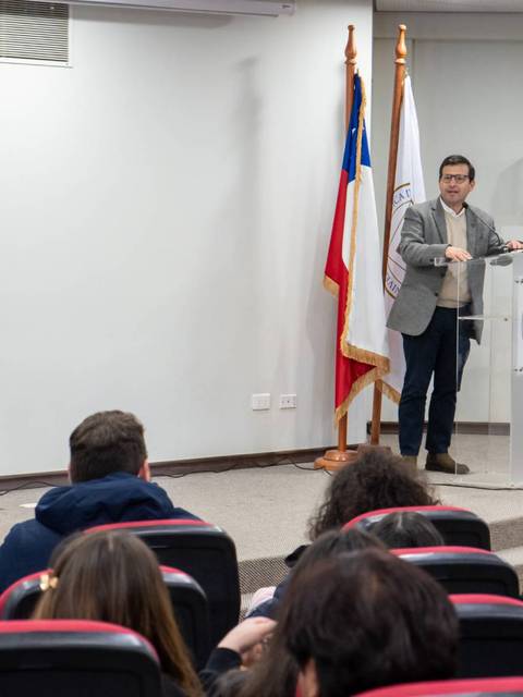 Un conferencista expositor presenta ante un grupo de personas en un auditorio.