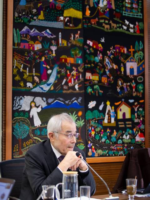 Una reunión en una sala decorada con un colorido mural chileno.