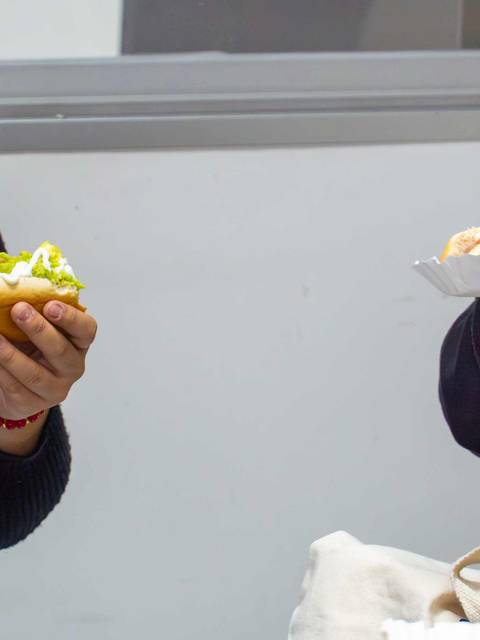 Dos personas disfrutando de completos en una reunión.