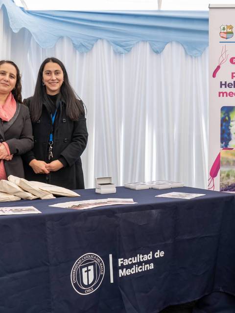 Dos mujeres posan sonrientes en un stand de prevención sobre Helicobacter Pylori.