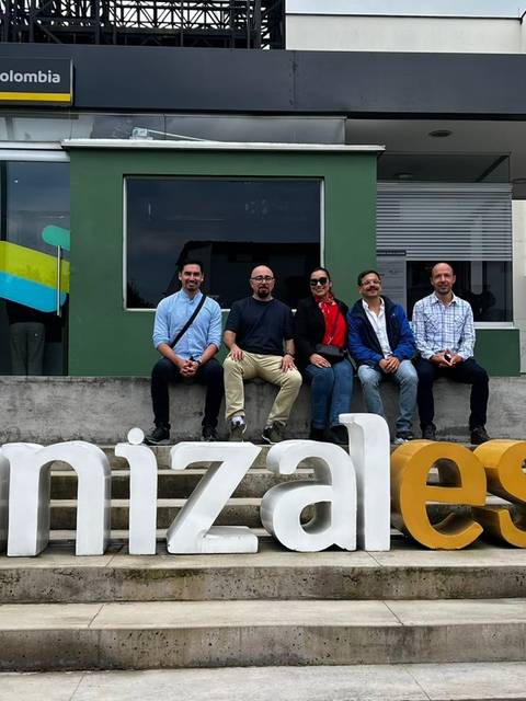 Un grupo de amigos posando frente al letrero de Manizales en un campus universitario.