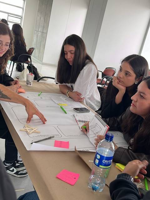 Un grupo de jóvenes se reúne en una mesa para trabajar en un proyecto mientras conversan animadamente.