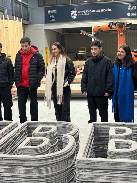 Un grupo de personas observa las letras en 3D de la UBB en un taller.