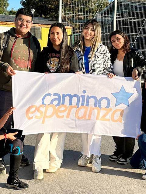 Un grupo de jóvenes sosteniendo una bandera con el lema 'camino esperanza'.