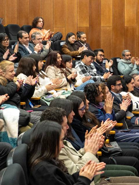 Un público aplaudiendo en un evento en un salón grande.