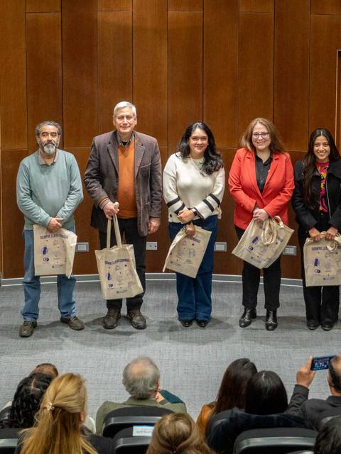 Un grupo de personas sonrientes sostiene bolsas en un evento de la Dirección de Igualdad de Género y Diversidad de la UCM.